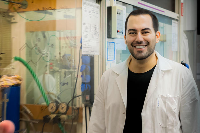 Student Armin Ariamajd in lab-coat in front of laboratory equipment