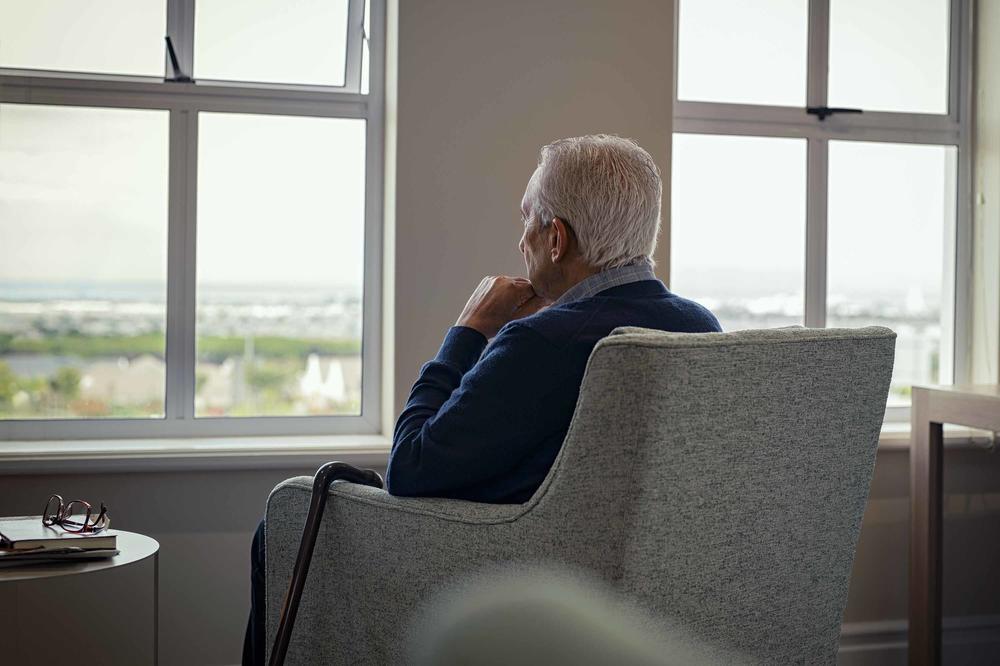 Mann im Rentenalter sitzt vor einem Fenster