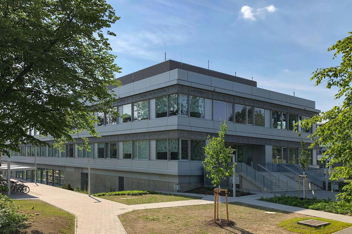 Grey modern building surrounded by trees on a sunny day